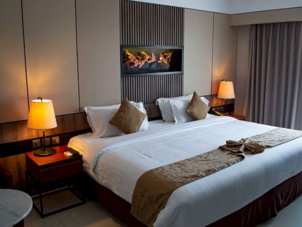 A hotel room with a neatly made bed, two bedside tables with lamps, wall art above the headboard, and a window with curtains.