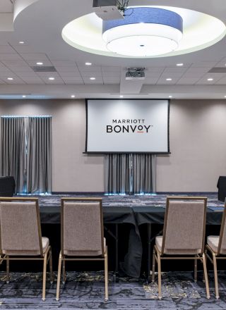 This image shows a conference room setup with chairs arranged in a U-shape, a projector screen displaying 