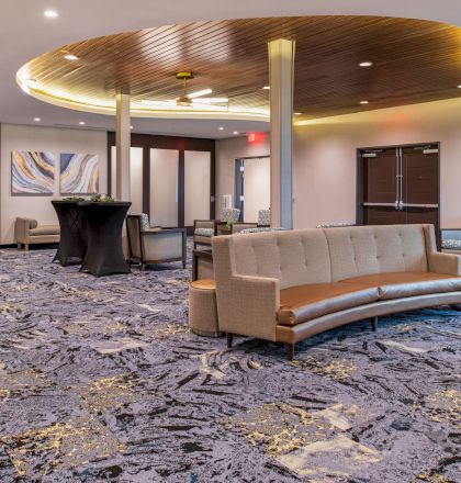 This image shows a modern, spacious lobby with contemporary furniture, patterned carpet, and decorative lighting, creating a welcoming atmosphere.